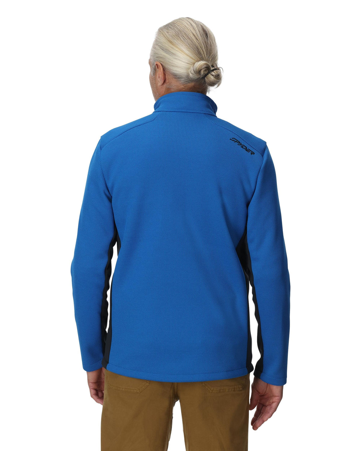 Person wearing a blue jacket with a visible brand logo on the back, standing against a white background.