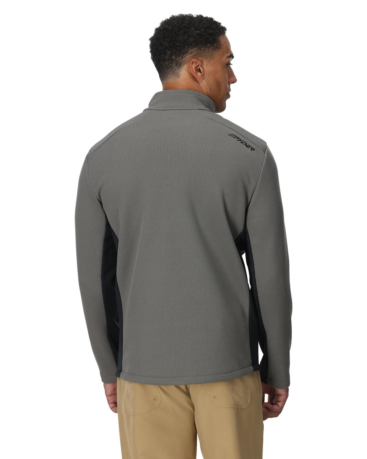 Man wearing a gray pullover with a brand logo on the back, standing against a white background