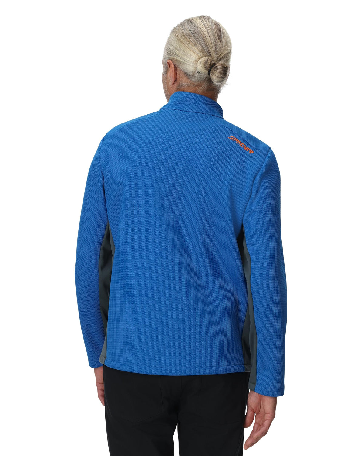 Person wearing a blue jacket with a visible brand logo on the back, standing against a white background.