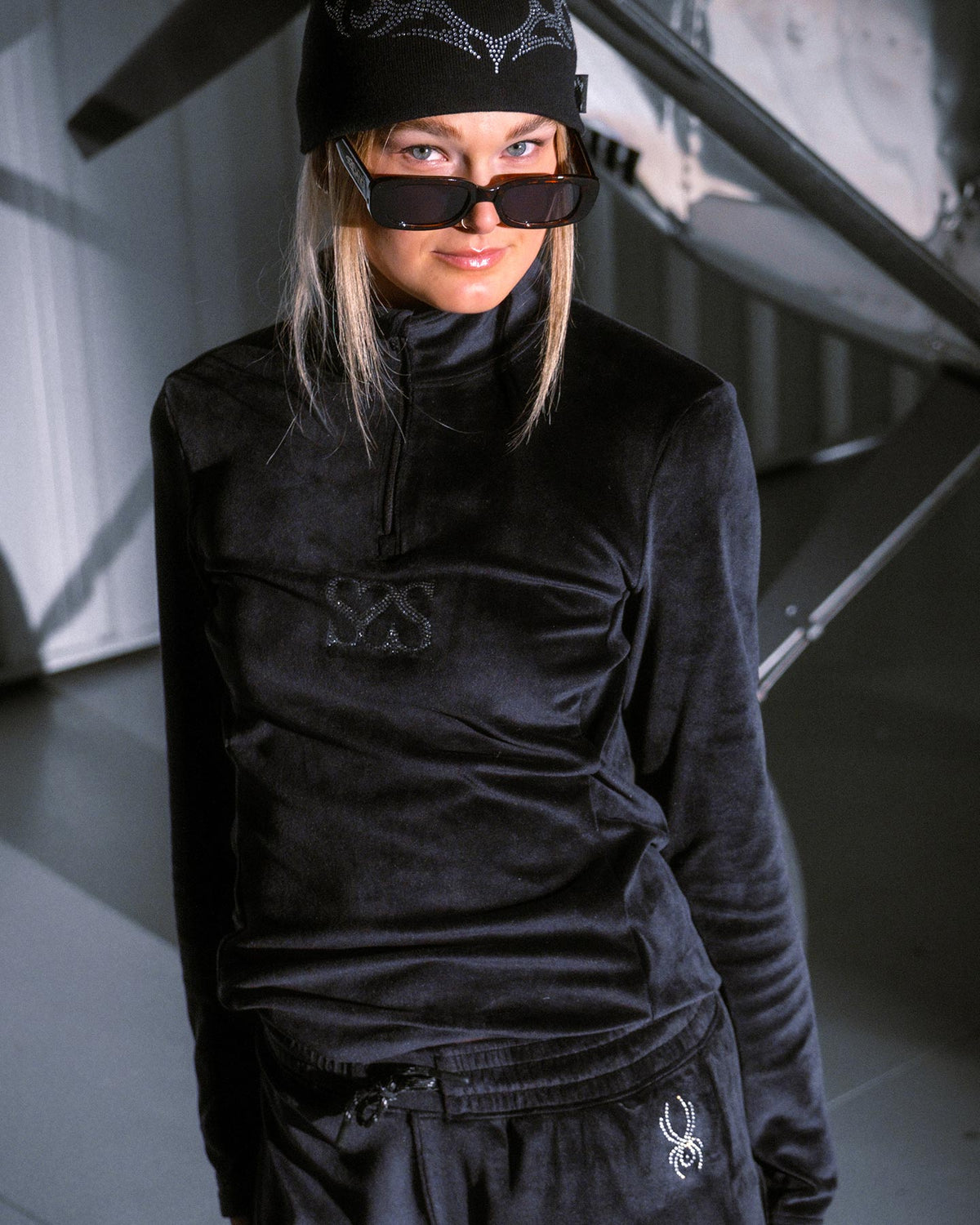 Person wearing a black outfit with logos in an indoor setting