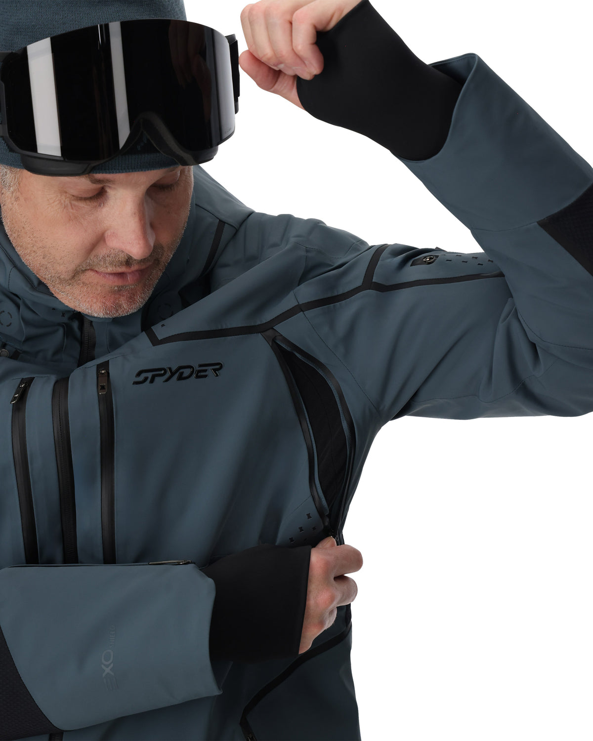 Person wearing a Spyder jacket and goggles on a white background