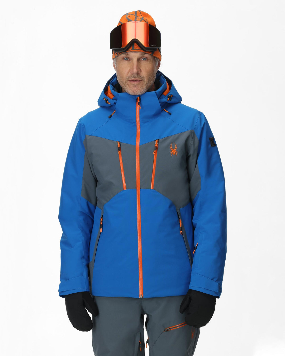 Person wearing a blue and gray ski jacket with orange accents on a white background