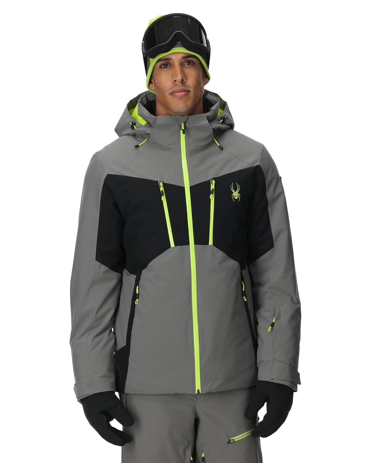 Person wearing a gray and black ski jacket with neon green accents on a white background