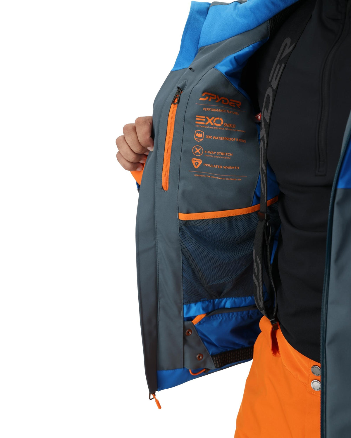 Close-up of a person wearing a blue, black, and orange jacket with visible branding on a white background.