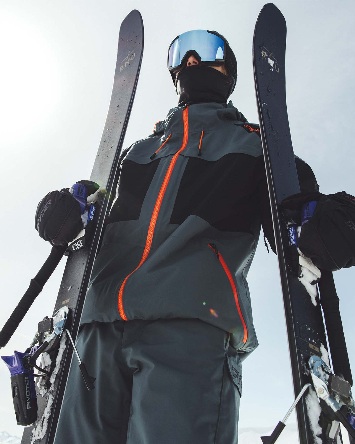 Person in ski gear holding skis against a snowy background