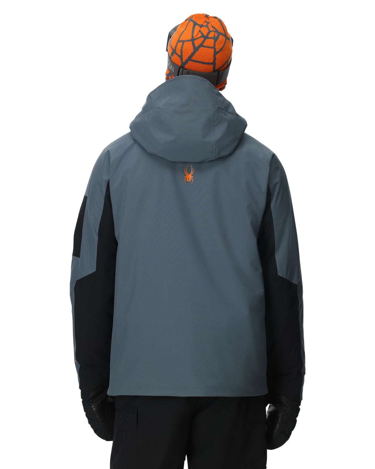 Person wearing a gray and black jacket with a hood, orange geometric-patterned beanie, and black gloves on a white background.
