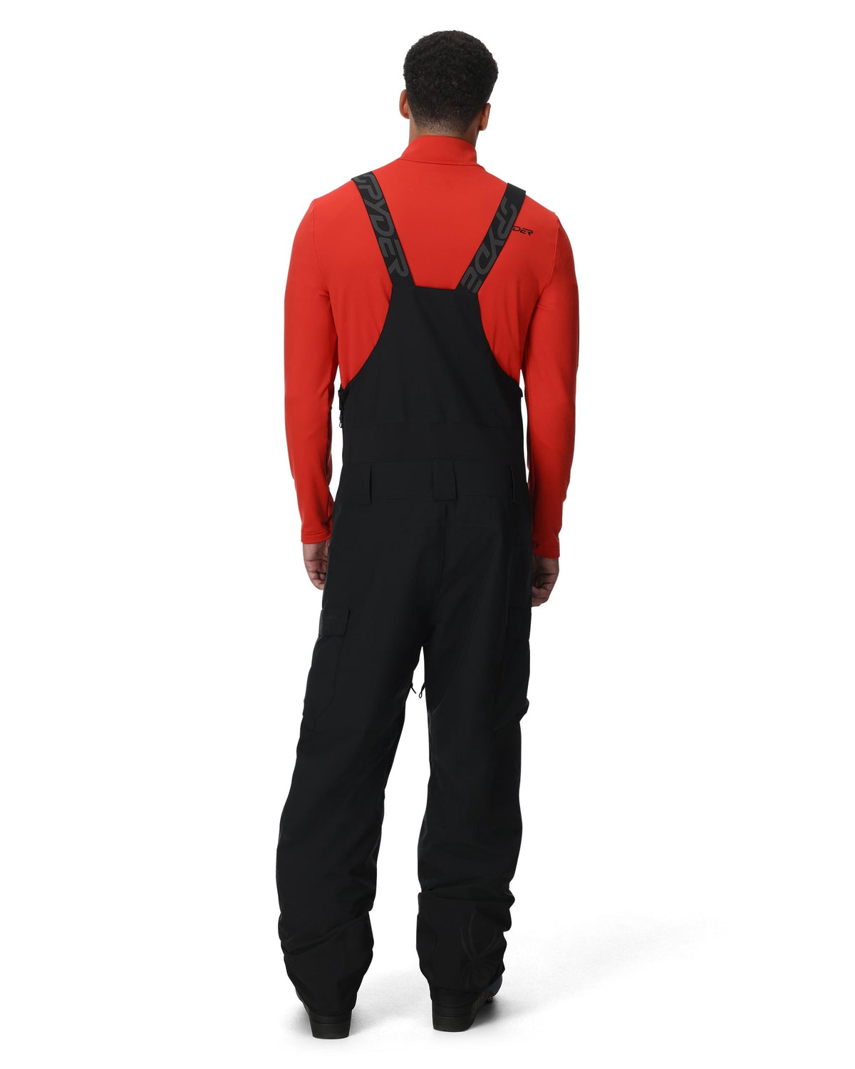 Person wearing a red long-sleeve shirt and black bib overalls on a white background