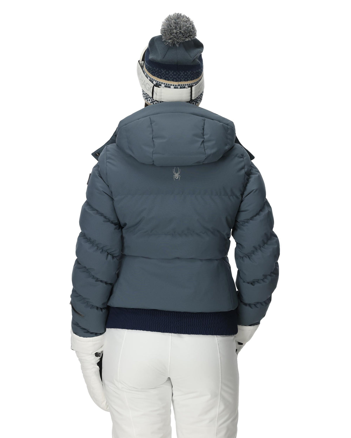 Person wearing a blue puffer jacket and white pants on a white background