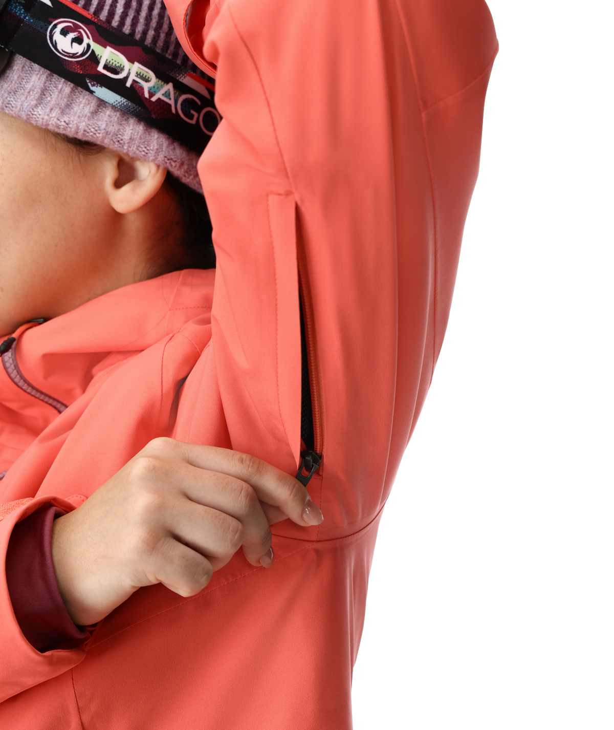 Person wearing a coral jacket with a brand logo on a white background
