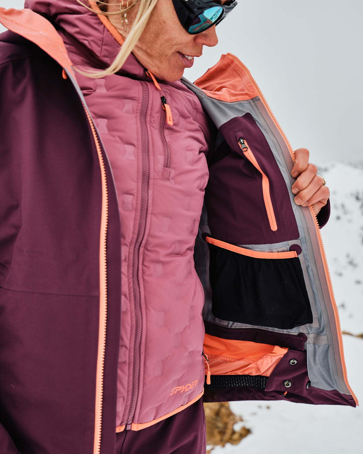Person wearing a purple and orange jacket with a backpack in a snowy landscape