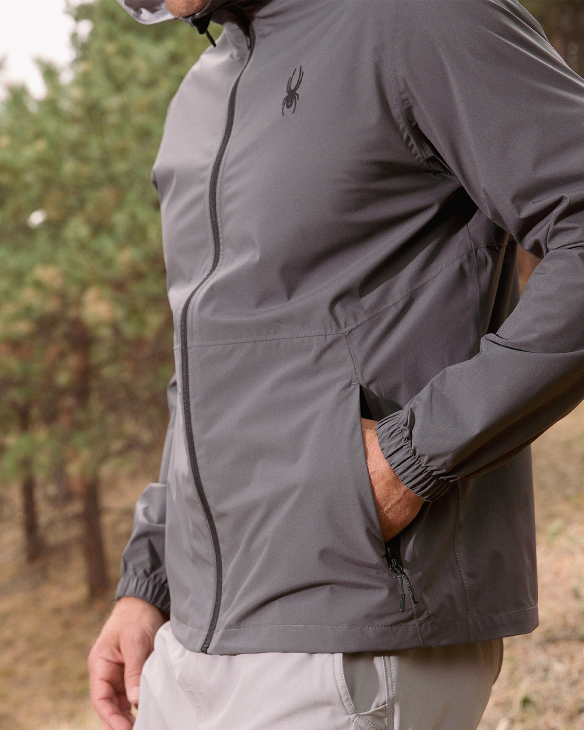 Person wearing a gray jacket with a brand logo outdoors