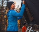 A woman in blue Spyder Gridweb Fleece setting up a tent outdoors with another person in the background.
