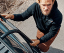 Man in a black Spyder x Reebok hoodie standing next to a vehicle.