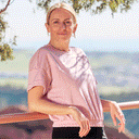 People in different outdoor settings: a woman on a scenic overlook, two skiers, and a man running.