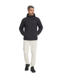 Man wearing a black quilted jacket and white pants on a white background