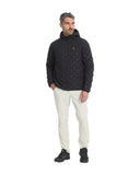 Man wearing a dark patterned jacket and light-colored pants on a white background