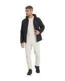Man wearing a black quilted jacket, white shirt, and beige pants on a white background