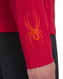 Red sleeve with orange spider logo on a person wearing black pants.