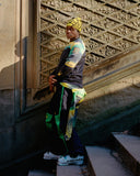 Person wearing a colorful outfit with a patterned wall in the background