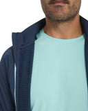 Man wearing a navy jacket over a light blue shirt on a white background