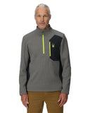 Man wearing a gray and black pullover with a logo on a white background