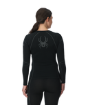 Person wearing a black long-sleeve athletic top with a logo on the back, on a white background
