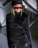 Person wearing a black outfit with logos in an indoor setting