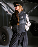 Person wearing a dark outfit with a logo in front of a vehicle
