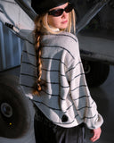 Person wearing a striped sweater and sunglasses with a vehicle in the background