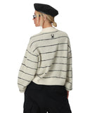 Person wearing a striped sweater with a spider logo on a white background