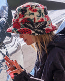 Person wearing a colorful floral-patterned bucket hat outdoors.