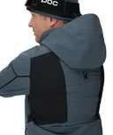 Person wearing a gray and black jacket with a hood, featuring a brand logo on the chest.