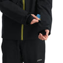 Person wearing a black jacket with yellow zipper details on a white background