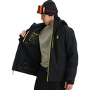 Person wearing a black jacket with yellow accents and a beanie, holding an open black jacket.