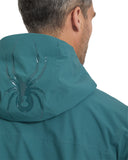 Teal jacket with a spider logo on the hood against a white background