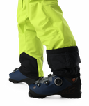 Close-up of bright yellow snow pants with black gaiters and blue ski boots on a white background