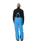 Person wearing blue snow pants with a black jacket on a white background