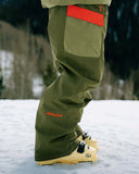Green snow pants with red accents and 'Venom' branding on a snowy ground.