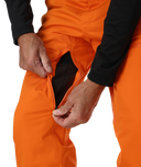 Person adjusting an orange snow pants with a white background