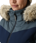 Close-up of a person wearing a blue and navy winter jacket with fur-lined hood.