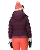 Person wearing a purple puffer jacket, orange pants, and a pink beanie with a white pom-pom on a white background