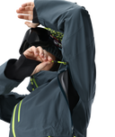 Person wearing a dark gray raincoat with yellow zippers on a white background