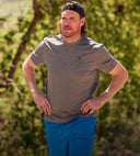 Runner wearing a Spyder gray t-shirt and blue shorts standing outdoors with greenery in the background