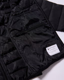 Close-up of a black puffer jacket with a brand label on a white background
